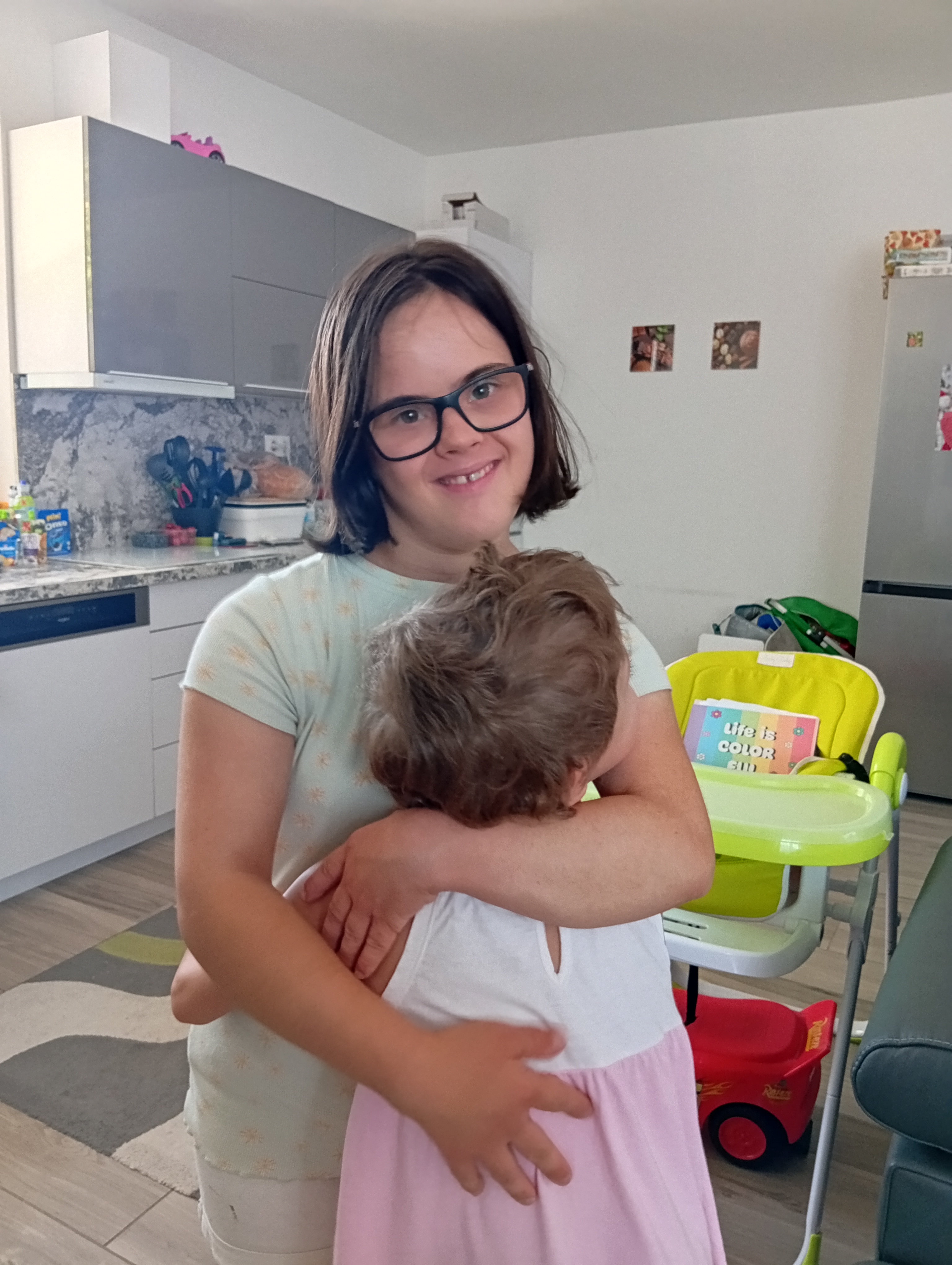 Mosolygó fiatal lány a karjában tartott kisgyermeket ölel